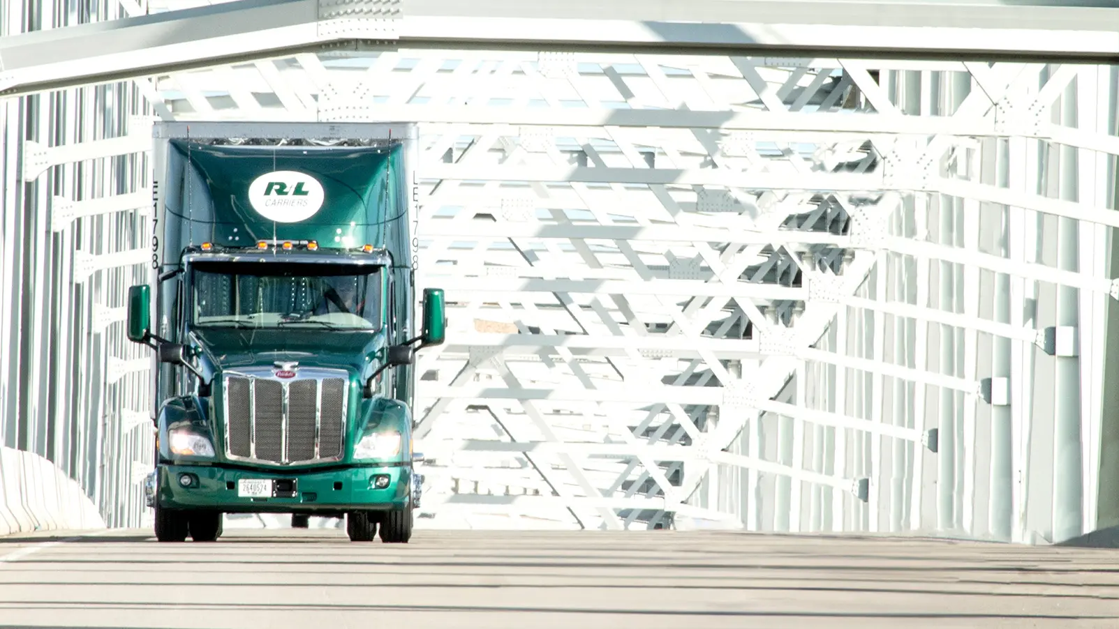 R+L Carriers LTL freight truck crossing a bridge in daylight.